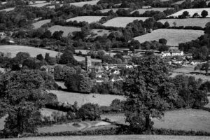 View over fields and trees towards the village of Huish Champflower. Black and white image.